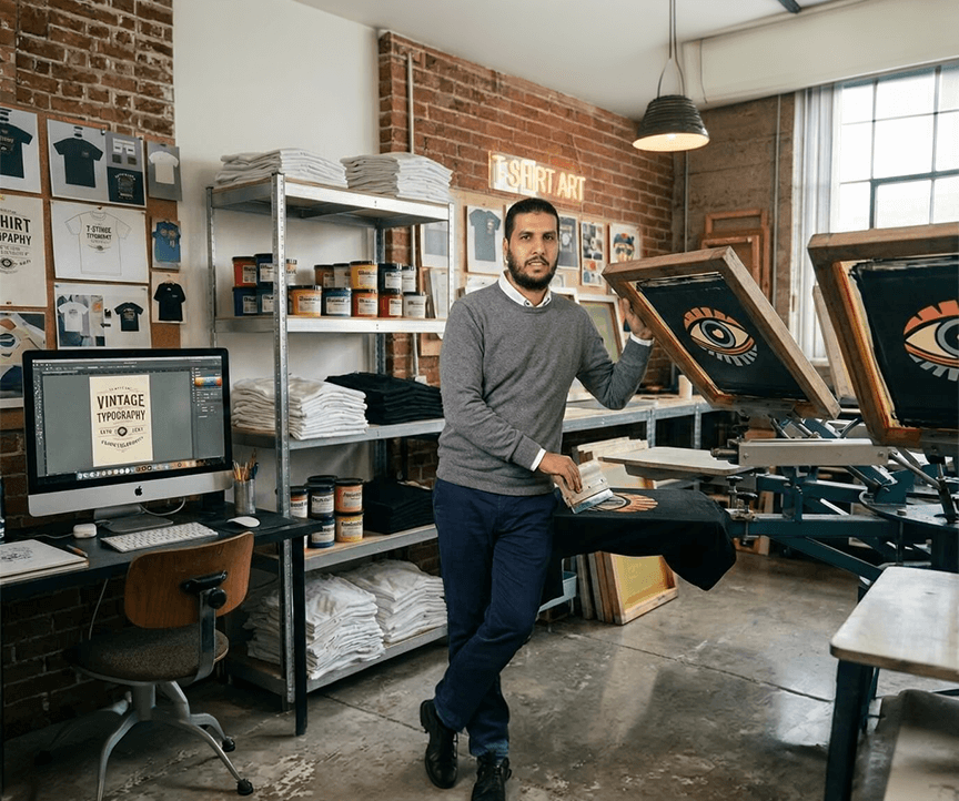 about us 5 Raafat Barakat working on custom t-shirt designs at his print-on-demand workspace – founder of Unique Stylistic Tee