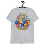 Male teacher wearing a white Curious Minds Club Teacher T-Shirt in an elementary classroom