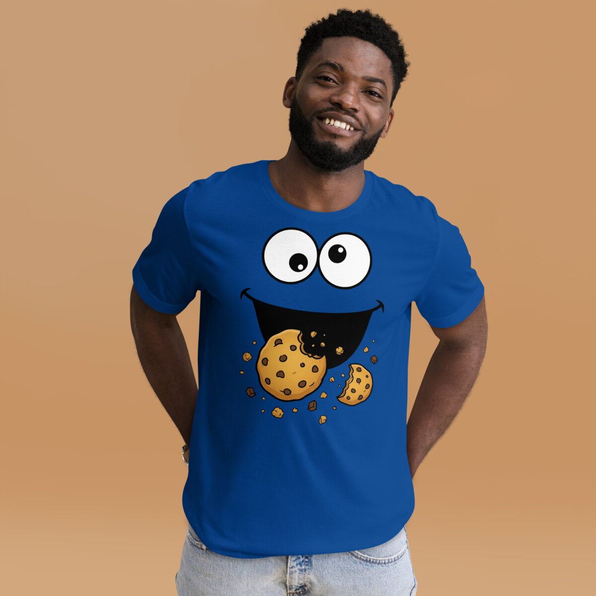 unisex-staple-t-shirt-true-royal-front-2-6ade6479c486d.jpg Male model wearing a blue Cookie Monster Shirt with googly eyes, a smiling mouth, chocolate chip cookies, and crumbs.